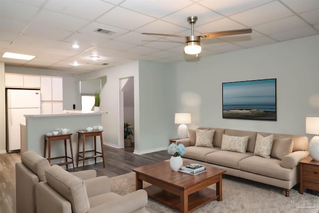 living room with light hardwood / wood-style floors, a drop ceiling, and ceiling fan