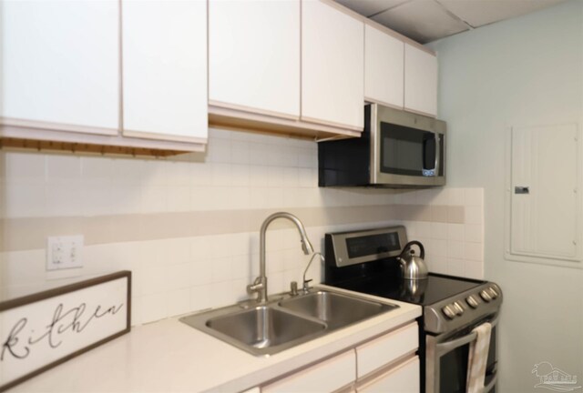 kitchen with sink, decorative backsplash, stainless steel appliances, and white cabinets