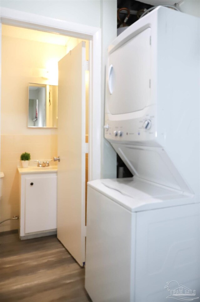 laundry area with wood-type flooring and stacked washer / drying machine