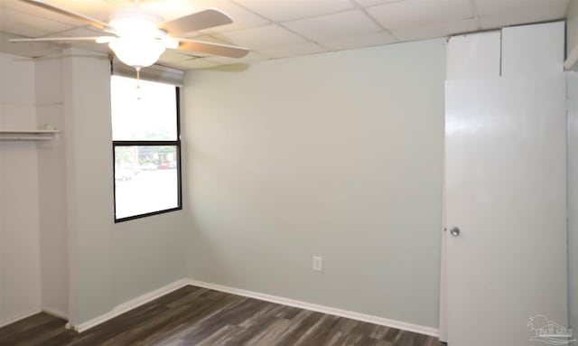 empty room with ceiling fan, a paneled ceiling, and dark hardwood / wood-style flooring