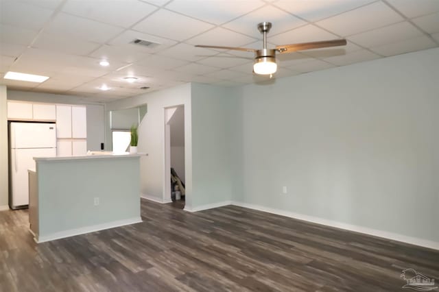 kitchen with white cabinets, ceiling fan, a paneled ceiling, hardwood / wood-style flooring, and white refrigerator