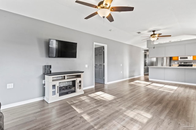 unfurnished living room with vaulted ceiling, hardwood / wood-style floors, and ceiling fan