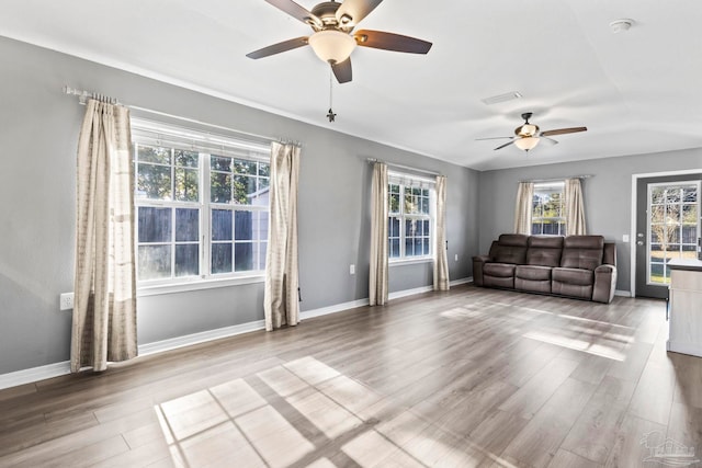 unfurnished living room featuring ceiling fan, hardwood / wood-style floors, and a wealth of natural light