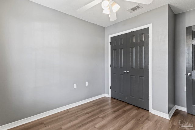 unfurnished bedroom featuring dark wood-type flooring, ceiling fan, and a closet