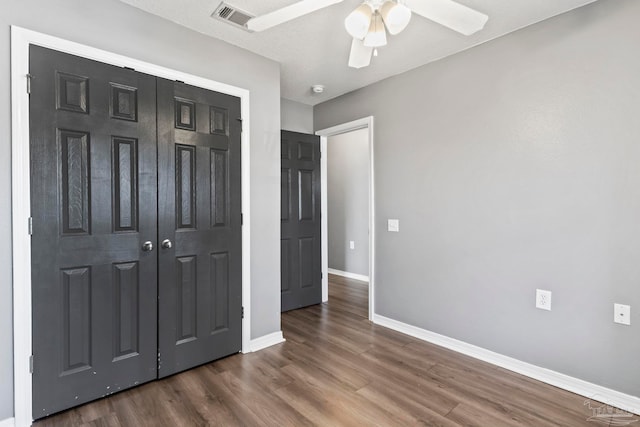 unfurnished bedroom with dark wood-type flooring, ceiling fan, and a closet