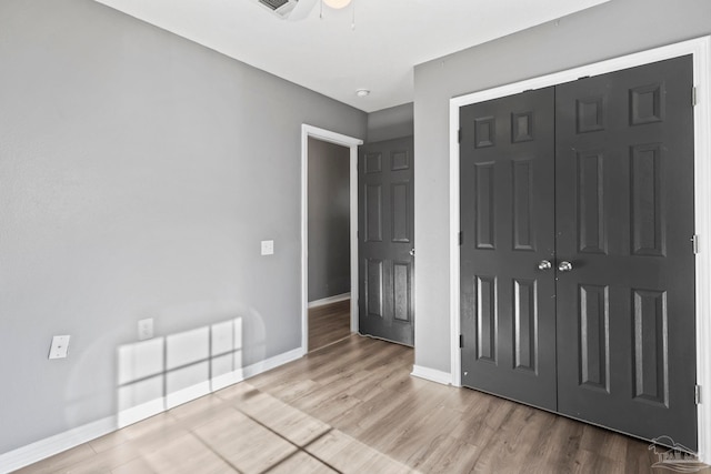 unfurnished bedroom with wood-type flooring, a closet, and ceiling fan