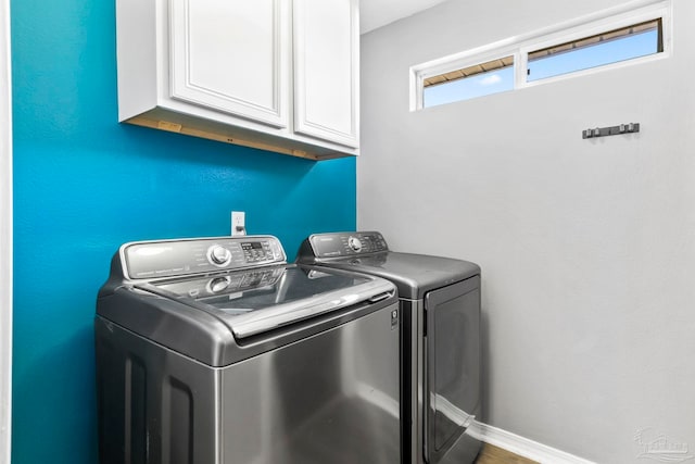 clothes washing area with cabinets and washing machine and clothes dryer