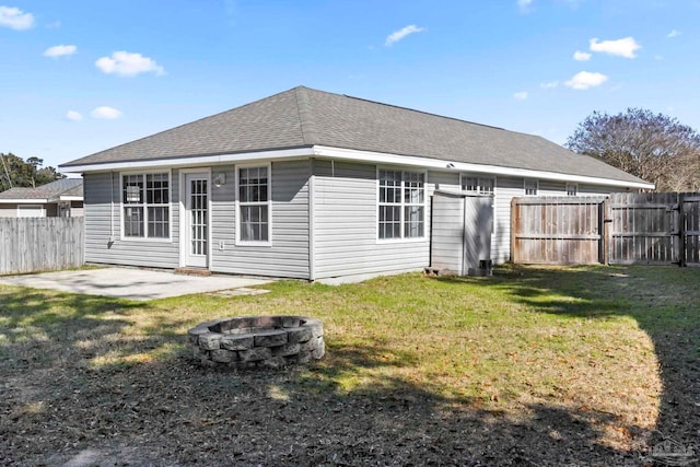 rear view of property with a yard, a fire pit, and a patio area