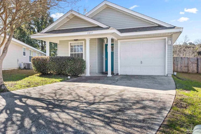 view of front of house featuring cooling unit, a garage, and covered porch