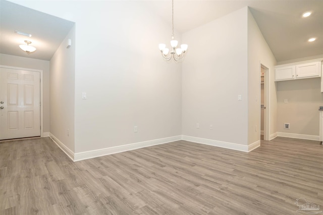 spare room featuring a notable chandelier and light hardwood / wood-style floors