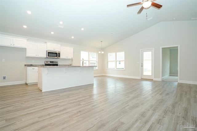 kitchen with a breakfast bar area, white cabinetry, a center island with sink, and appliances with stainless steel finishes