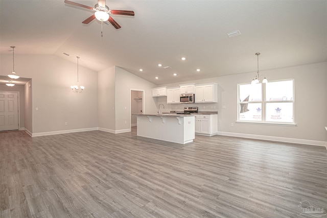 unfurnished living room featuring vaulted ceiling, hardwood / wood-style floors, and ceiling fan with notable chandelier