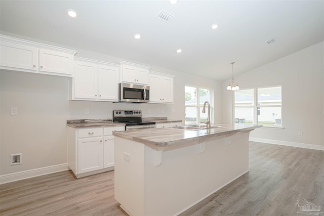 kitchen featuring white cabinetry, sink, an island with sink, lofted ceiling, and appliances with stainless steel finishes