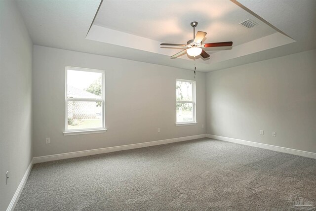 carpeted spare room featuring a raised ceiling and ceiling fan