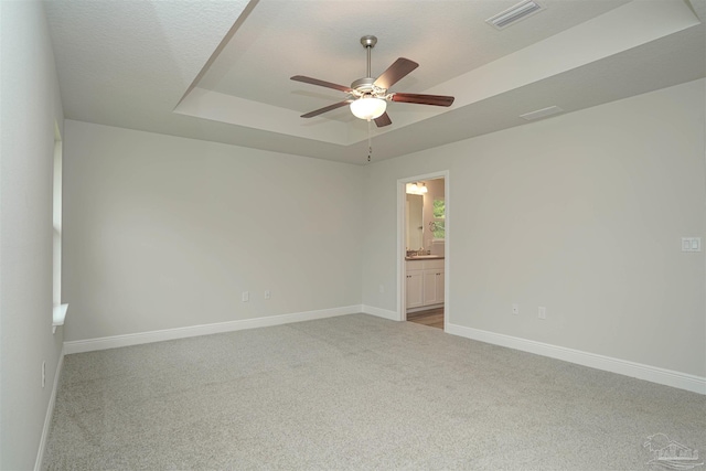 carpeted empty room featuring ceiling fan and a tray ceiling