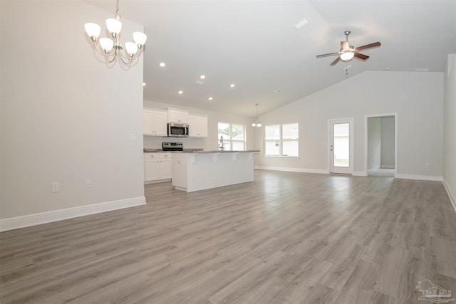 unfurnished living room with light wood-type flooring, ceiling fan with notable chandelier, high vaulted ceiling, and sink