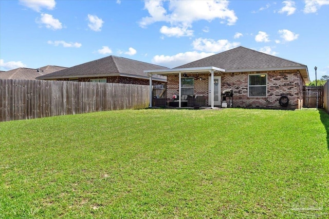 3966 Willow Glen Dr, Pace, FL 32571 - back of property featuring roof with shingles, brick siding, a fenced backyard, and a lawn
