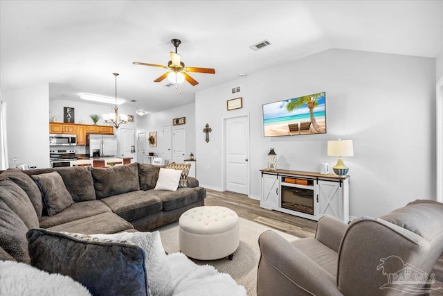 3966 Willow Glen Dr, Pace, FL 32571 - living room featuring baseboards, visible vents, lofted ceiling, light wood finished floors, and ceiling fan with notable chandelier
