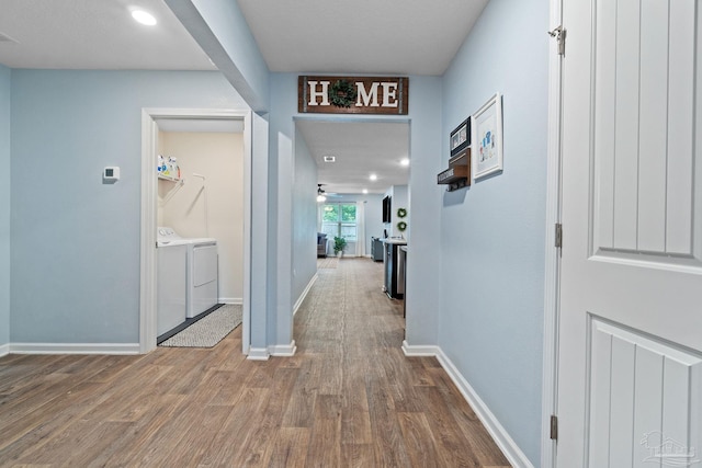 hall with wood finished floors, washer and dryer, visible vents, and baseboards
