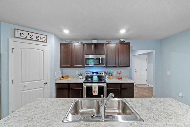 kitchen with a sink, dark brown cabinets, appliances with stainless steel finishes, and light countertops