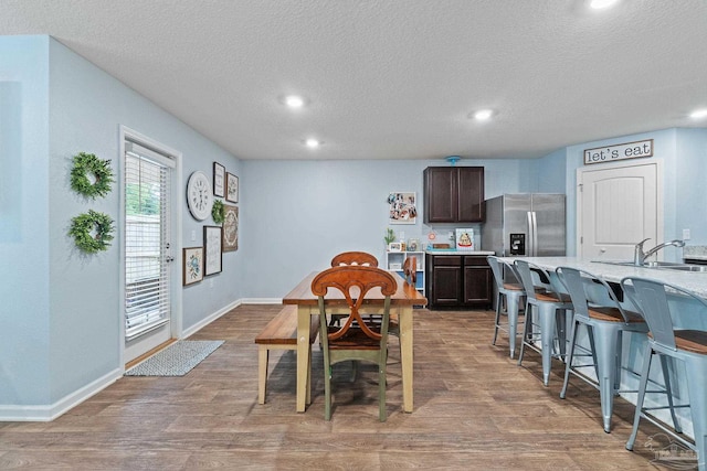 dining area with a textured ceiling, wood finished floors, and recessed lighting
