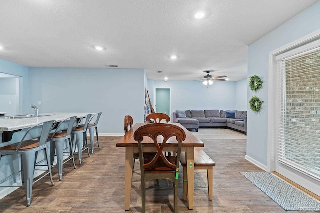 dining area featuring a textured ceiling, a ceiling fan, wood finished floors, and baseboards