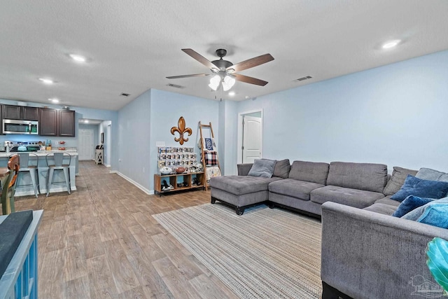 living room featuring recessed lighting, light wood-style floors, a ceiling fan, visible vents, and baseboards