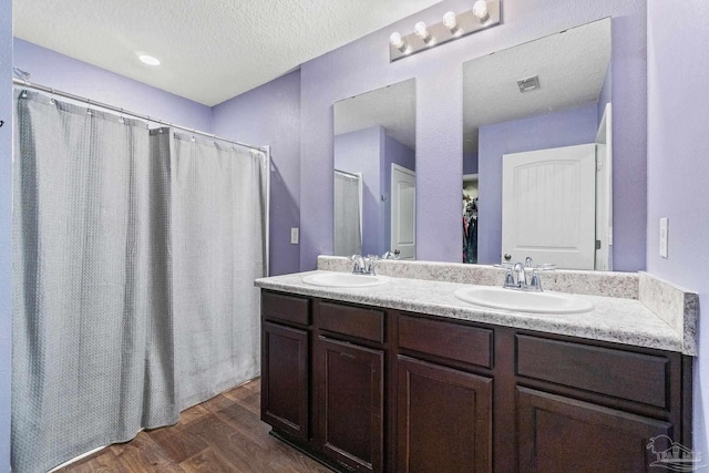 full bathroom with visible vents, wood finished floors, double vanity, and a sink