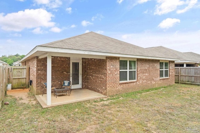 back of house featuring a fenced backyard, brick siding, a patio, roof with shingles, and a lawn