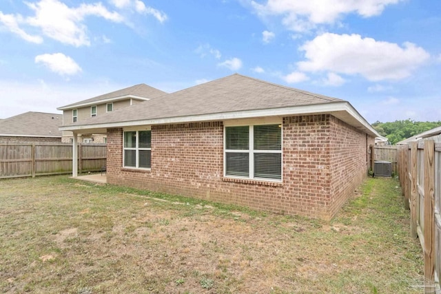 back of property featuring a yard, a shingled roof, brick siding, and a fenced backyard