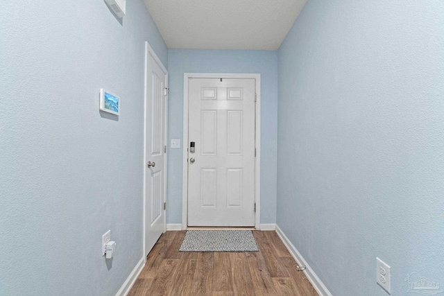 doorway with wood finished floors and baseboards