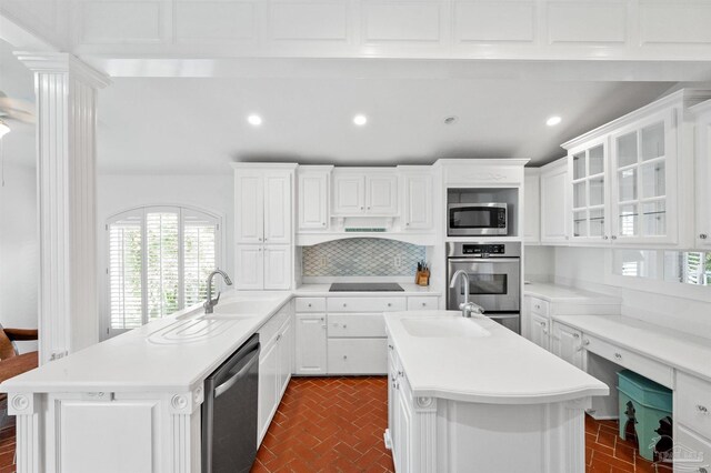 kitchen featuring white cabinets, stainless steel appliances, and an island with sink