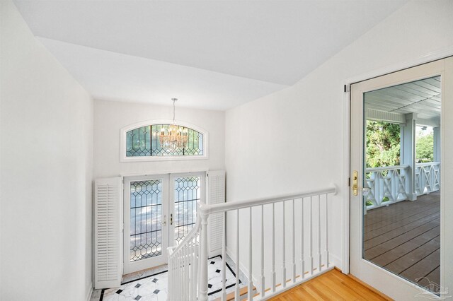 interior space with french doors, lofted ceiling, hardwood / wood-style flooring, and a notable chandelier