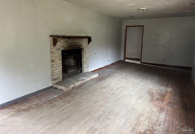 unfurnished living room featuring a fireplace, hardwood / wood-style floors, and a textured ceiling