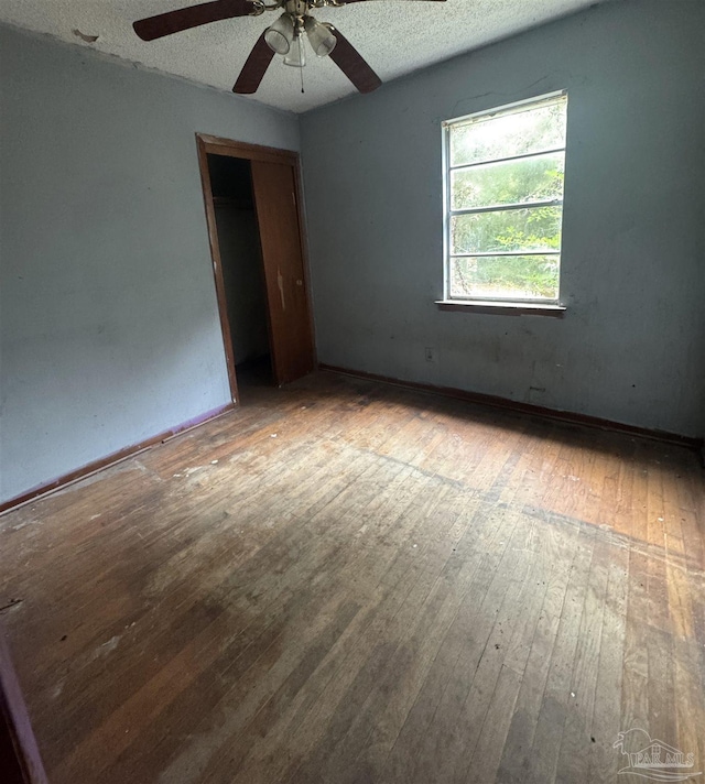 spare room with a textured ceiling, hardwood / wood-style flooring, and ceiling fan