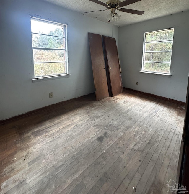 unfurnished bedroom featuring a textured ceiling, ceiling fan, light hardwood / wood-style flooring, and multiple windows