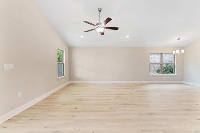 empty room with light hardwood / wood-style flooring, lofted ceiling, and ceiling fan with notable chandelier