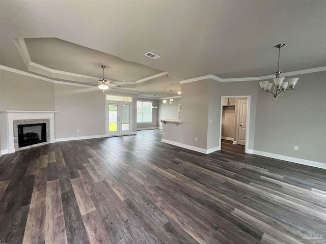 unfurnished living room with ceiling fan with notable chandelier, ornamental molding, dark hardwood / wood-style floors, and a tray ceiling