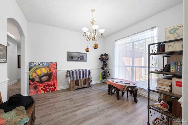 rec room with a chandelier, arched walkways, a textured ceiling, and wood finished floors