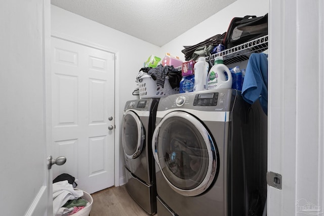 laundry room with a textured ceiling, laundry area, light wood finished floors, and washing machine and dryer