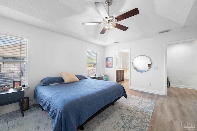 bedroom with a textured ceiling, light wood finished floors, visible vents, and baseboards