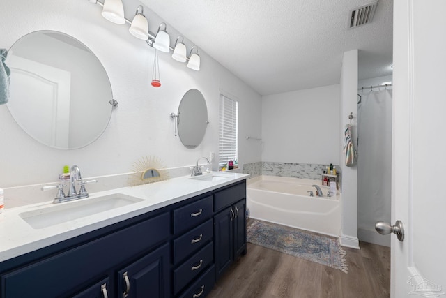 full bath featuring a textured ceiling, wood finished floors, a sink, and visible vents