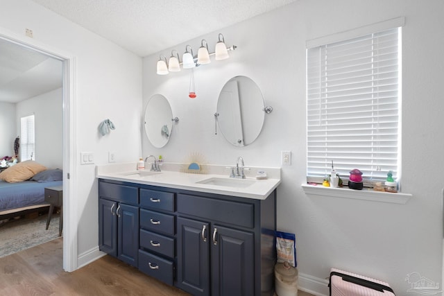 full bath featuring double vanity, a textured ceiling, a sink, and wood finished floors