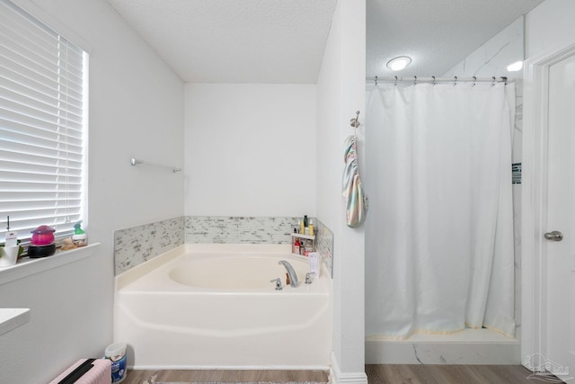 bathroom featuring a garden tub, a shower stall, a textured ceiling, and wood finished floors