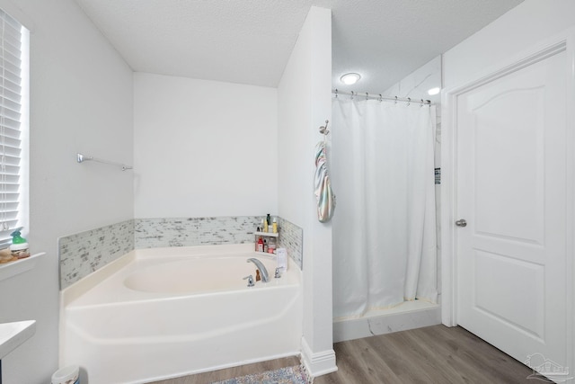 full bathroom with a garden tub, a shower stall, a textured ceiling, and wood finished floors