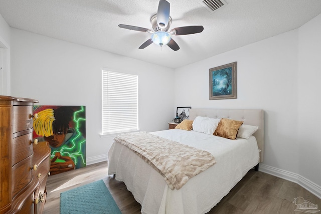 bedroom with dark wood-style floors, baseboards, visible vents, and a textured ceiling