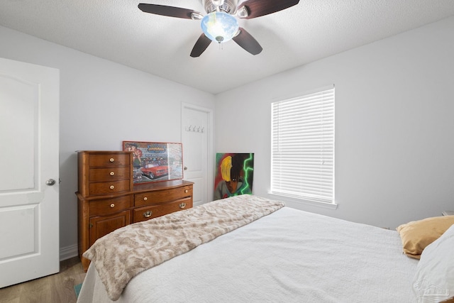 bedroom featuring a textured ceiling, ceiling fan, and wood finished floors