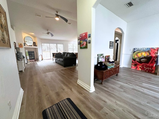 hall with arched walkways, visible vents, and wood finished floors