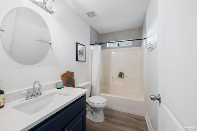 bathroom with a textured ceiling, toilet, wood finished floors, vanity, and visible vents