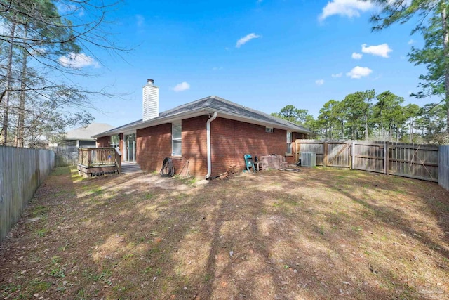 rear view of property featuring a chimney, brick siding, a yard, and a fenced backyard